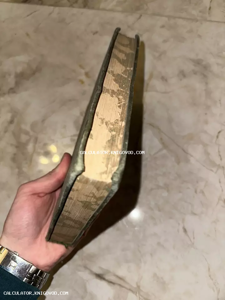Вид сверху на обрез старой книги с крапчатым узором в руке человека на фоне мраморной поверхности.