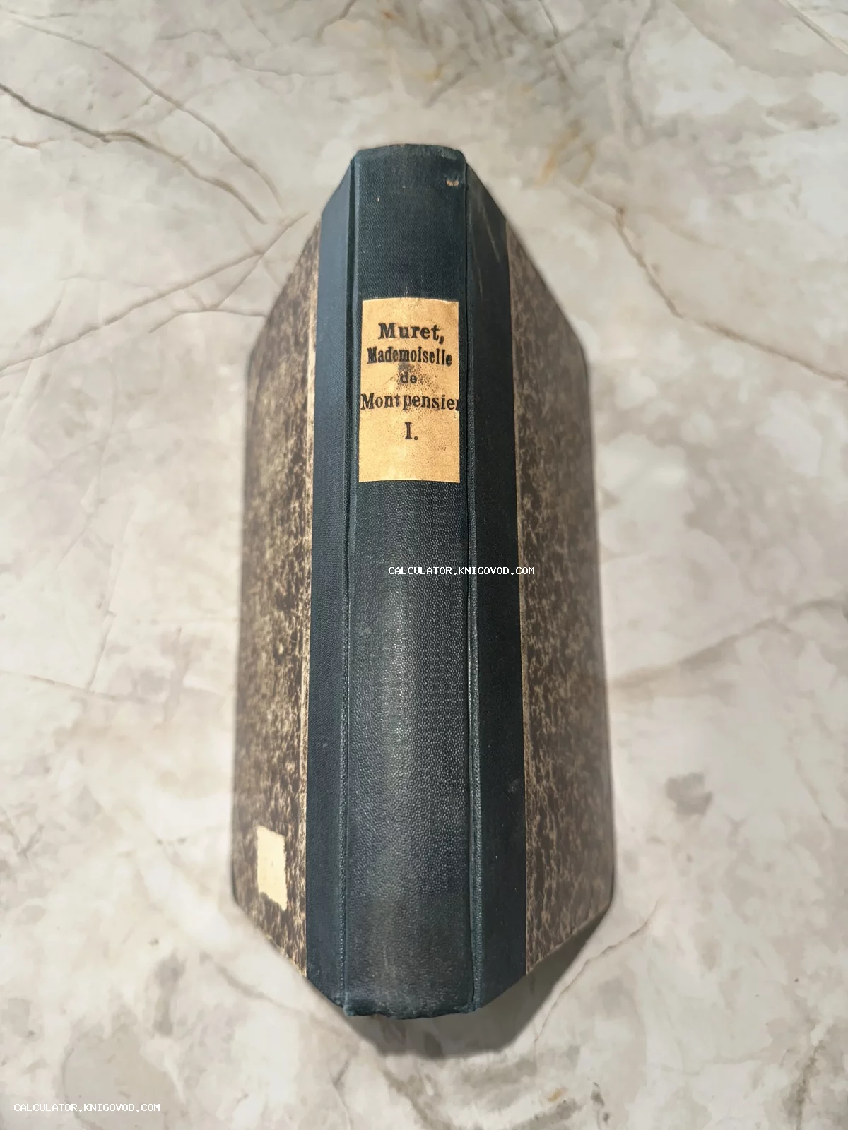 Старинная книга в полукожаном переплете с мраморной бумагой на обложке и бумажной этикеткой на корешке.