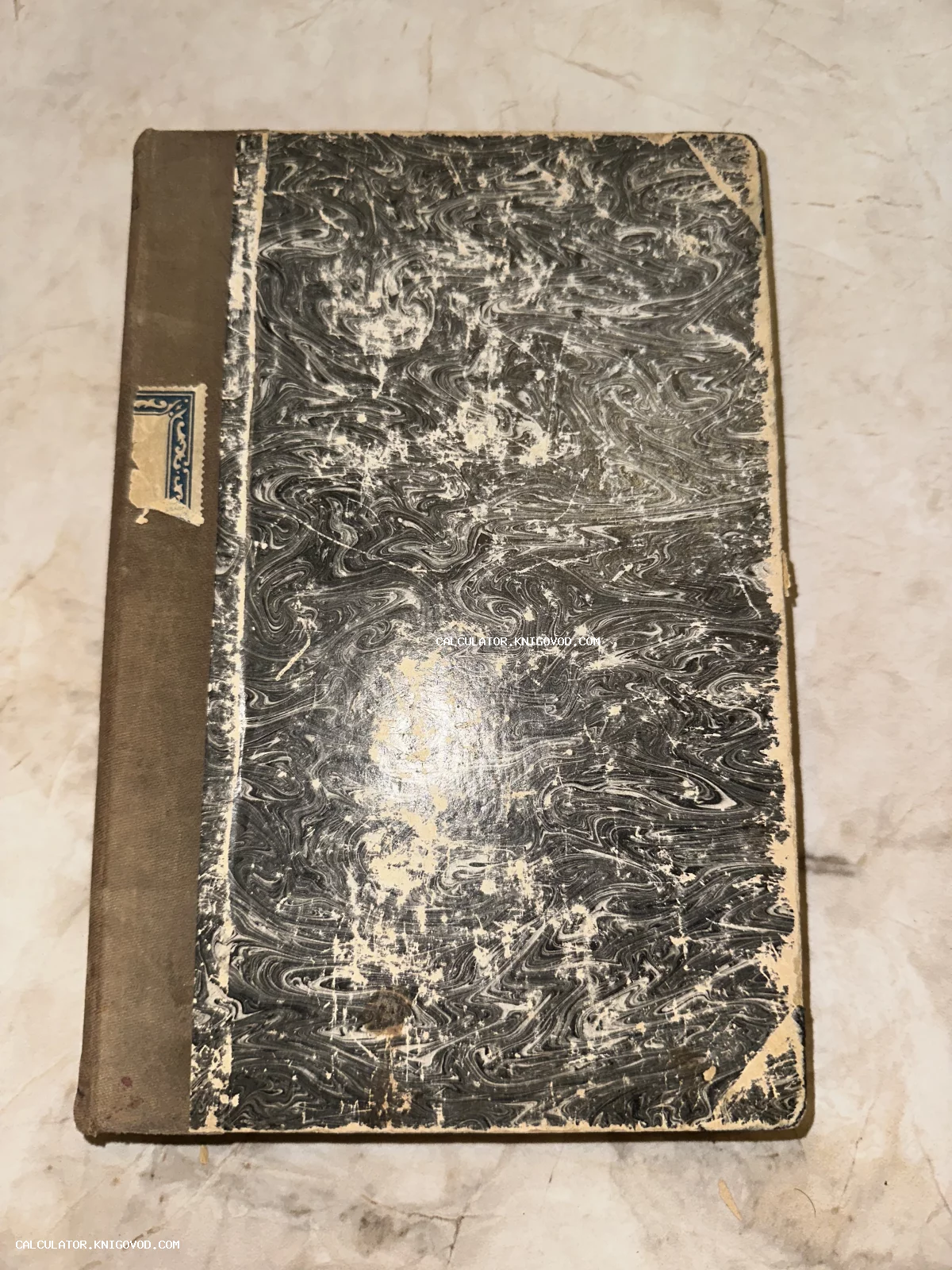 Вид сверху на антикварную книгу с обложкой из мраморной бумаги ручной работы и тканевым корешком.