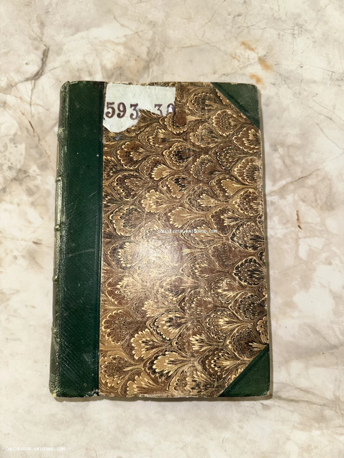 Старинная книга с зеленым кожаным корешком и узором 'павлинье перо' на обложке.