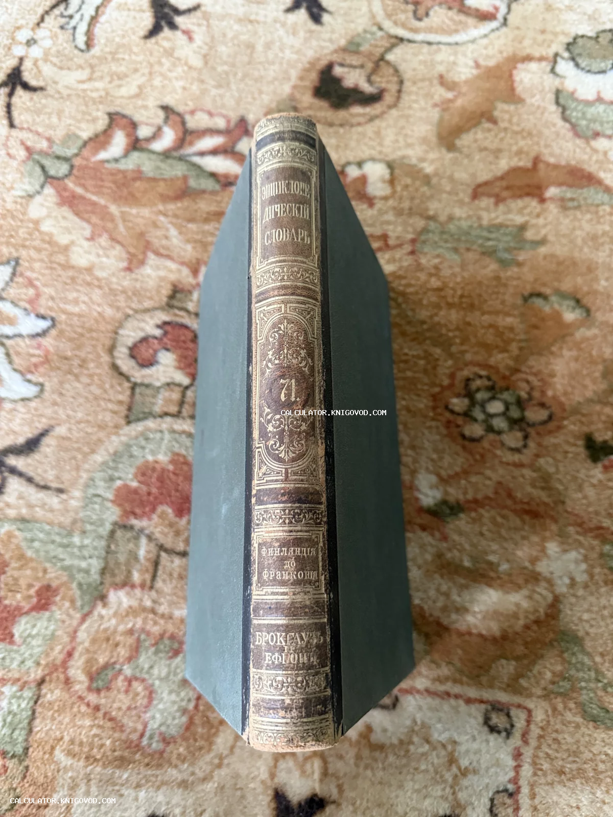 Корешок антикварной книги Энциклопедический словарь Брокгауза и Ефрона, том 71, с золотым тиснением на фоне восточного ковра.