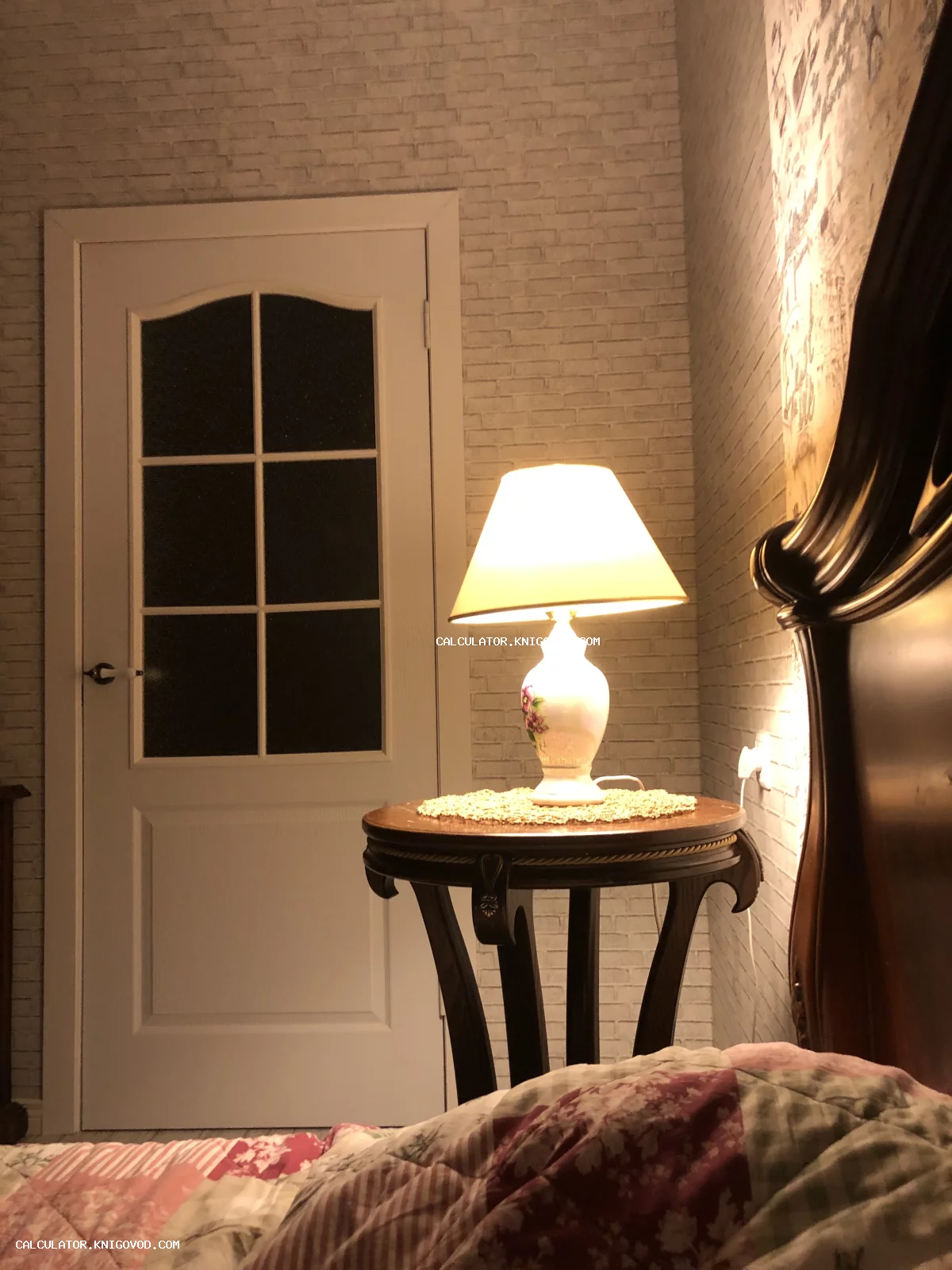 Классическая настольная лампа с керамическим основанием и цветочным декором на круглом деревянном столике.