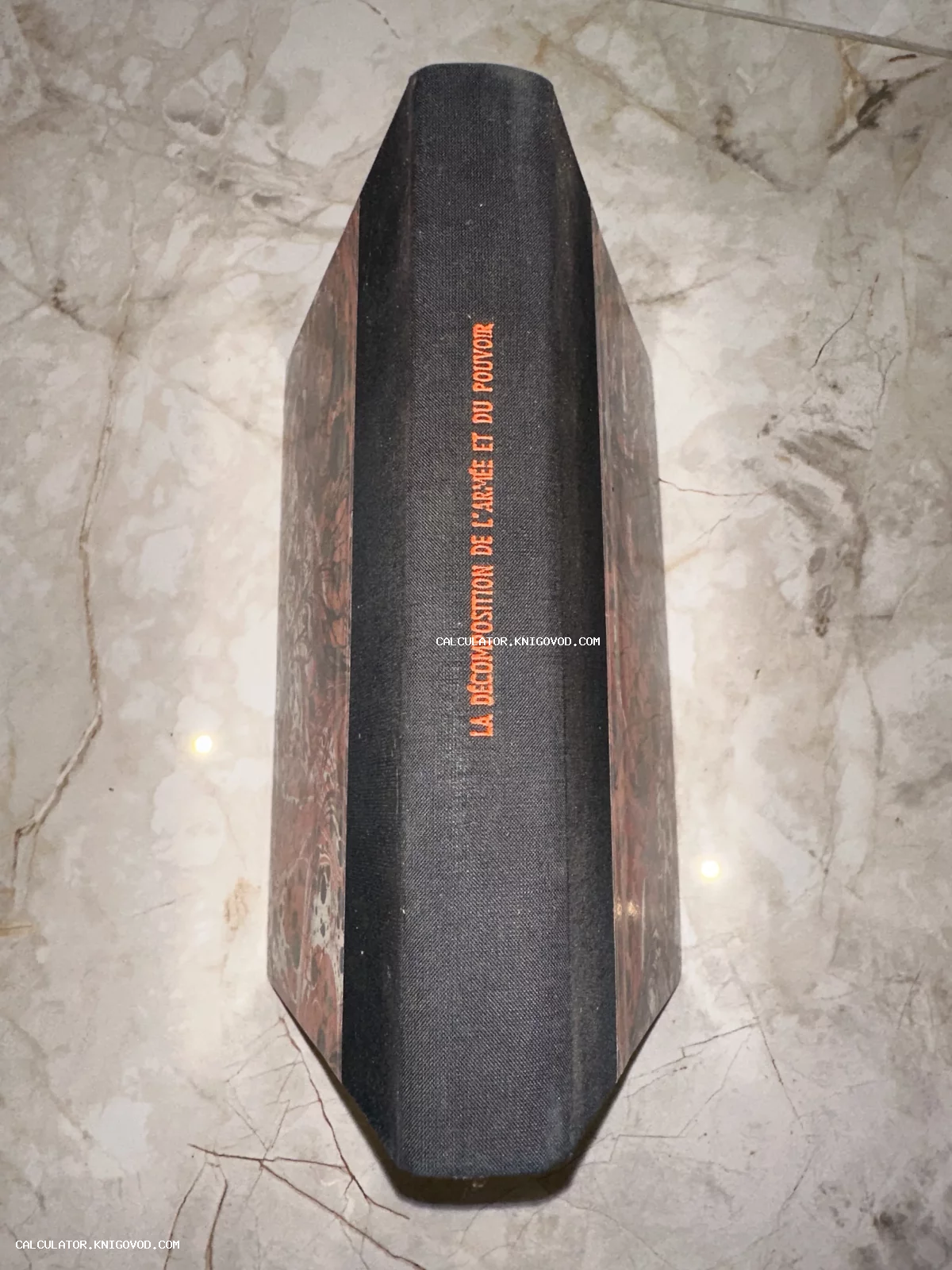 Корешок антикварной книги в черном тканевом переплете с оранжевым тиснением на французском языке.