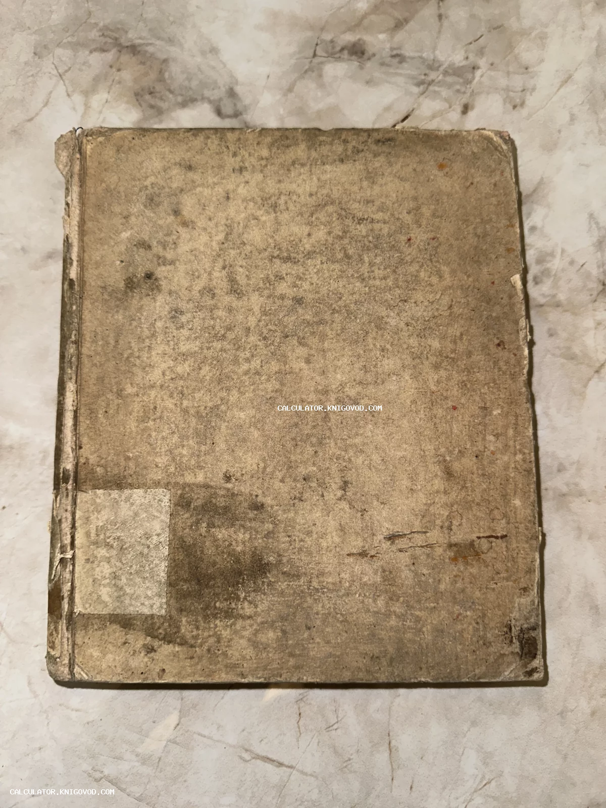 Вид сверху на обложку старинной антикварной книги с сильными потертостями, пятнами и следами бытования.