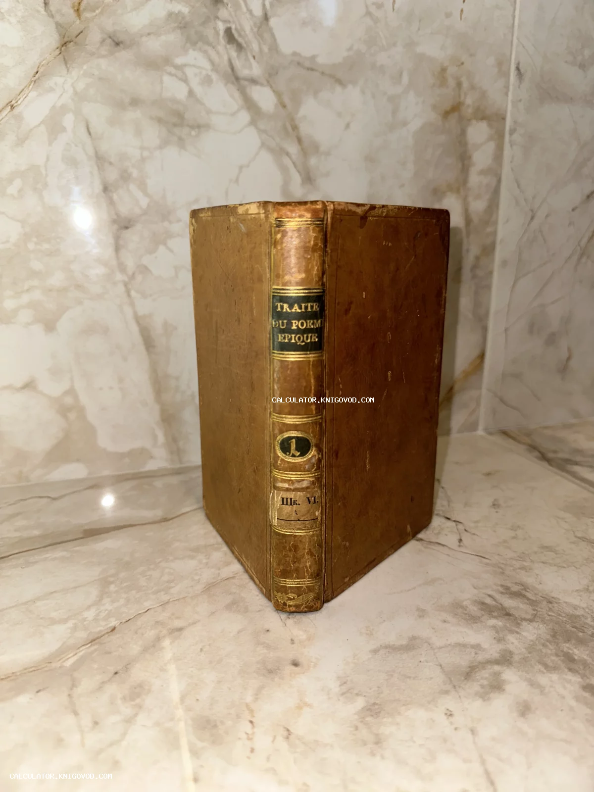 Старинная книга в кожаном переплете с золотым тиснением на корешке, название Traite du poème épique, на фоне мрамора.