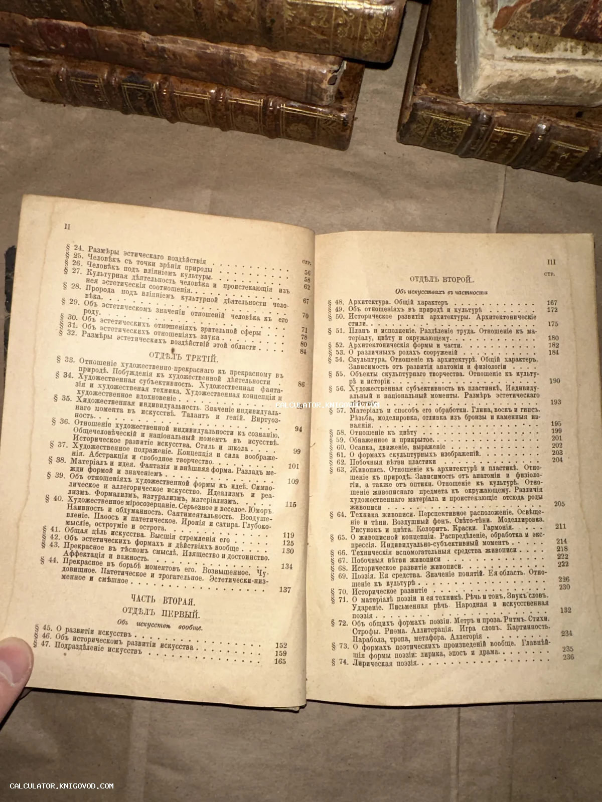 Страницы старинной книги с оглавлением на дореволюционном русском языке, лежащей на фоне кожаных книжных переплетов.