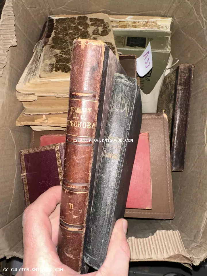 Старинные книги в картонной коробке, рука держит 11 том сочинений Лескова в кожаном переплете с золотым тиснением.