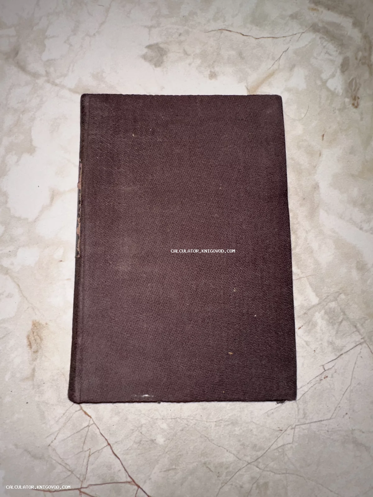 Антикварная книга в темно-коричневой тканевой обложке на мраморном фоне