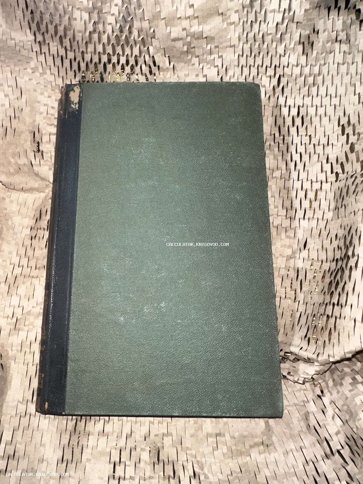 Старинная книга с зеленой фактурной обложкой и темным корешком на упаковочной бумаге.