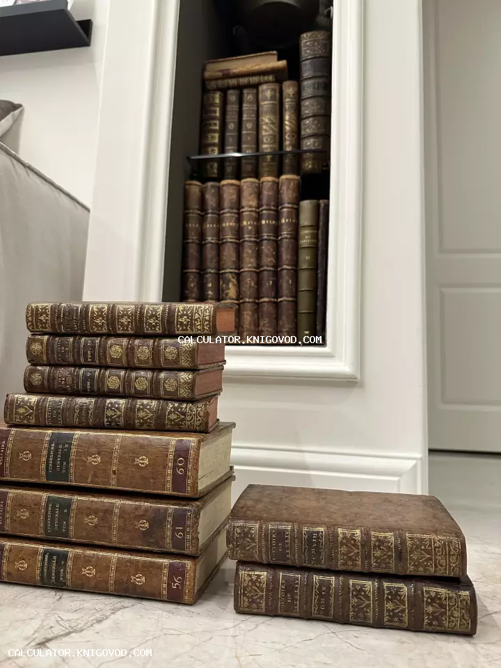 Старинные книги в кожаных переплетах с золотым тиснением, сложенные стопками на фоне белой ниши с книжными полками.