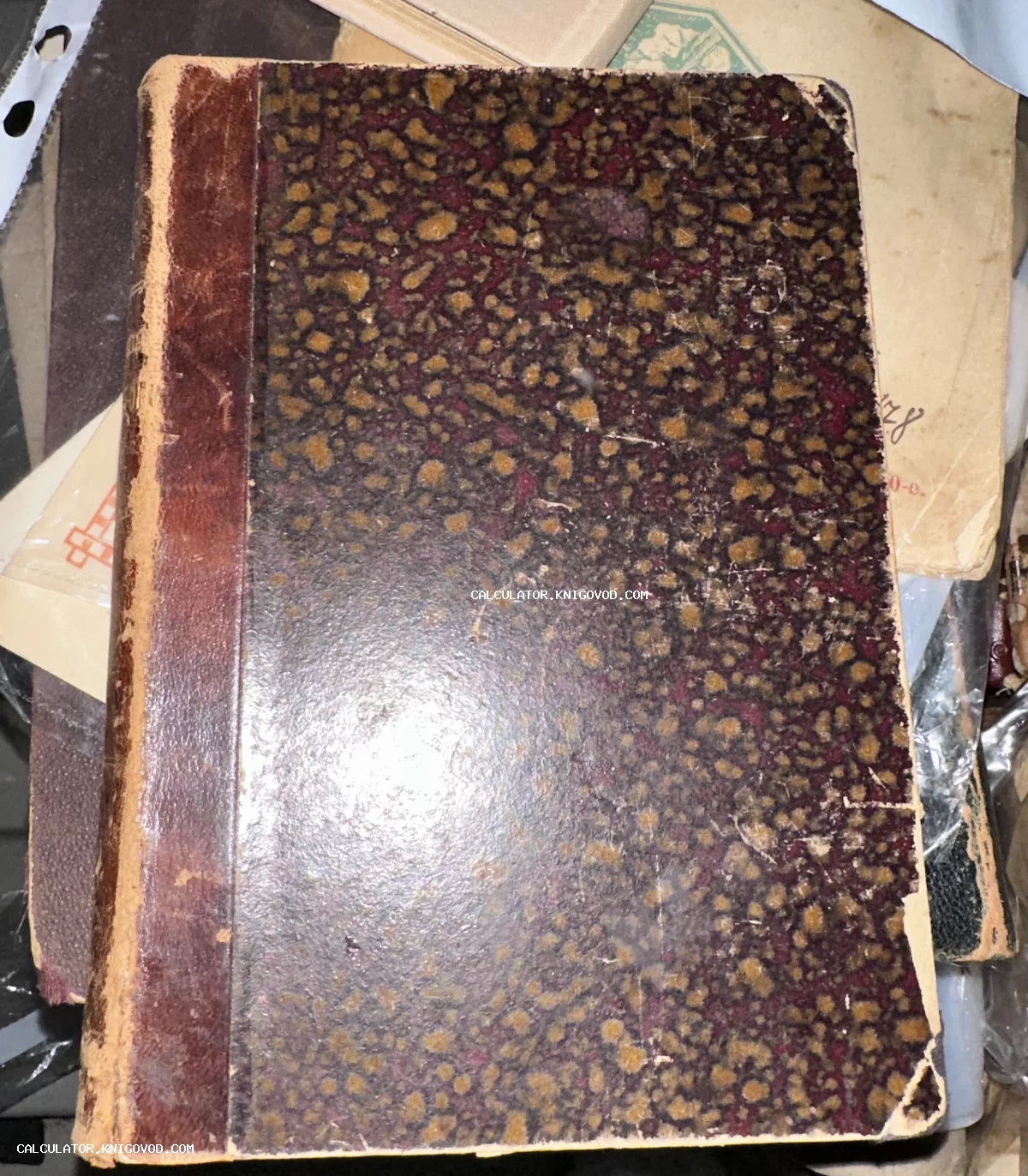 Старинная книга с кожаным корешком и обложкой с пятнистым коричнево-бордовым узором «под мрамор»