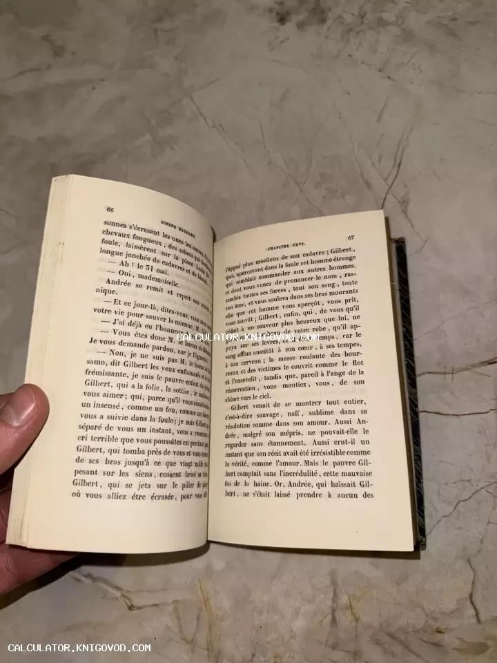 Разворот старинной книги на французском языке с текстом романа Жозеф Бальзамо на фоне мраморного стола.