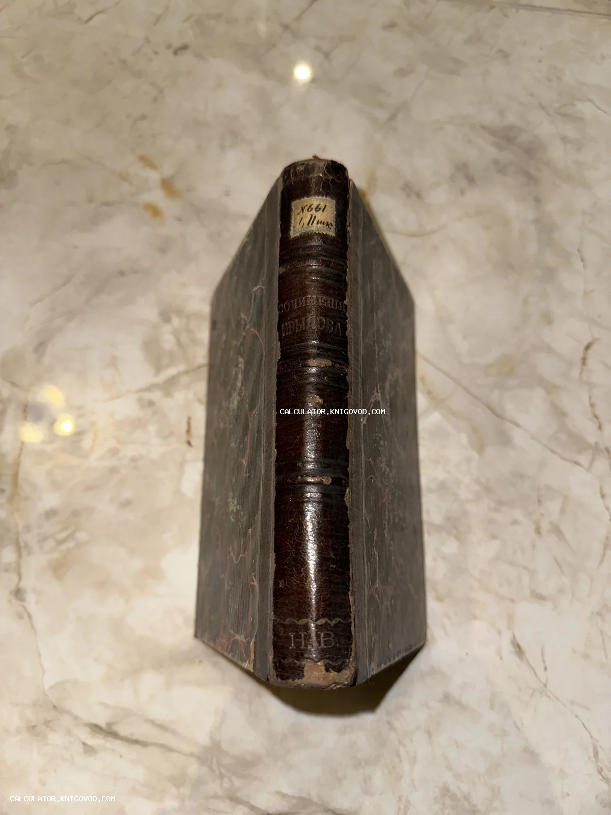 Вид на корешок антикварной книги 'Сочинения Крылова' с золотым тиснением и следами бытования на мраморном фоне.