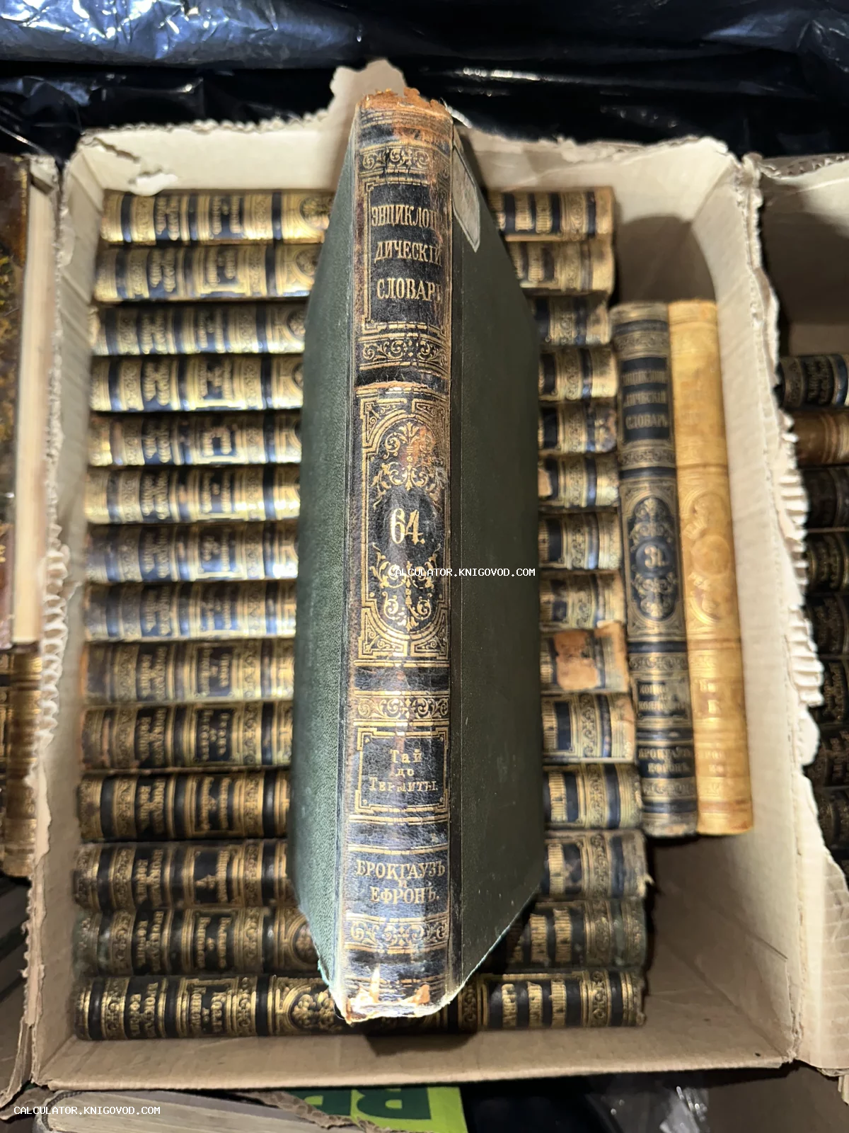 Собрание антикварных книг Брокгауза и Ефрона в коробке, крупный план корешка 64 тома с золотым тиснением.