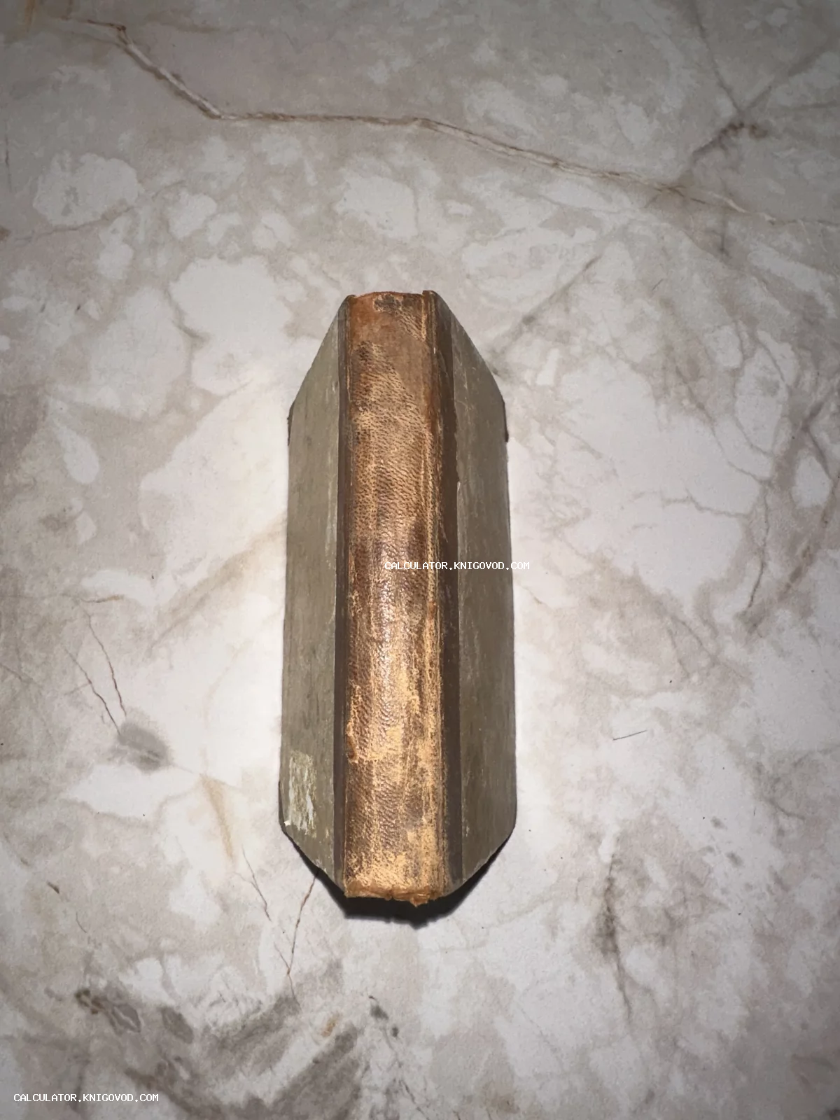 Вид сверху на потертый корешок антикварной книги, лежащей на мраморном столе