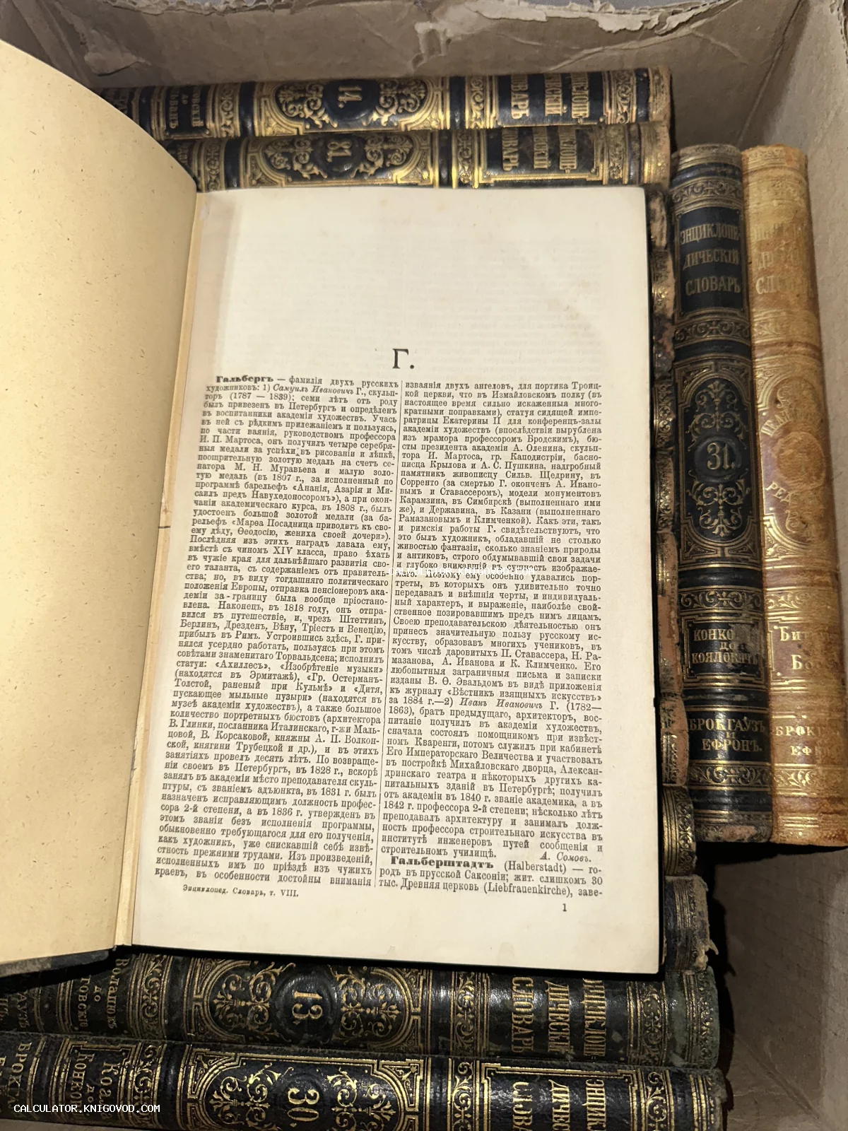 Раскрытая старинная книга с дореволюционным шрифтом на фоне стопки томов в кожаных переплетах с золотым тиснением.