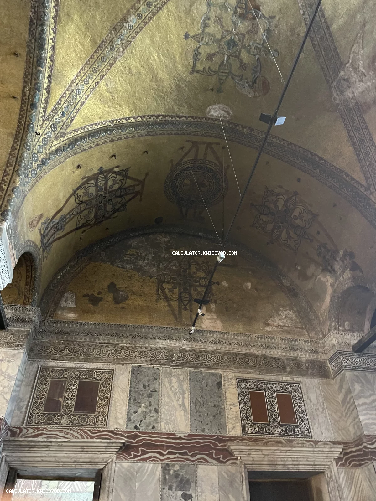 Фрагмент интерьера древнего собора с золотыми мозаичными сводами и мраморными панелями.