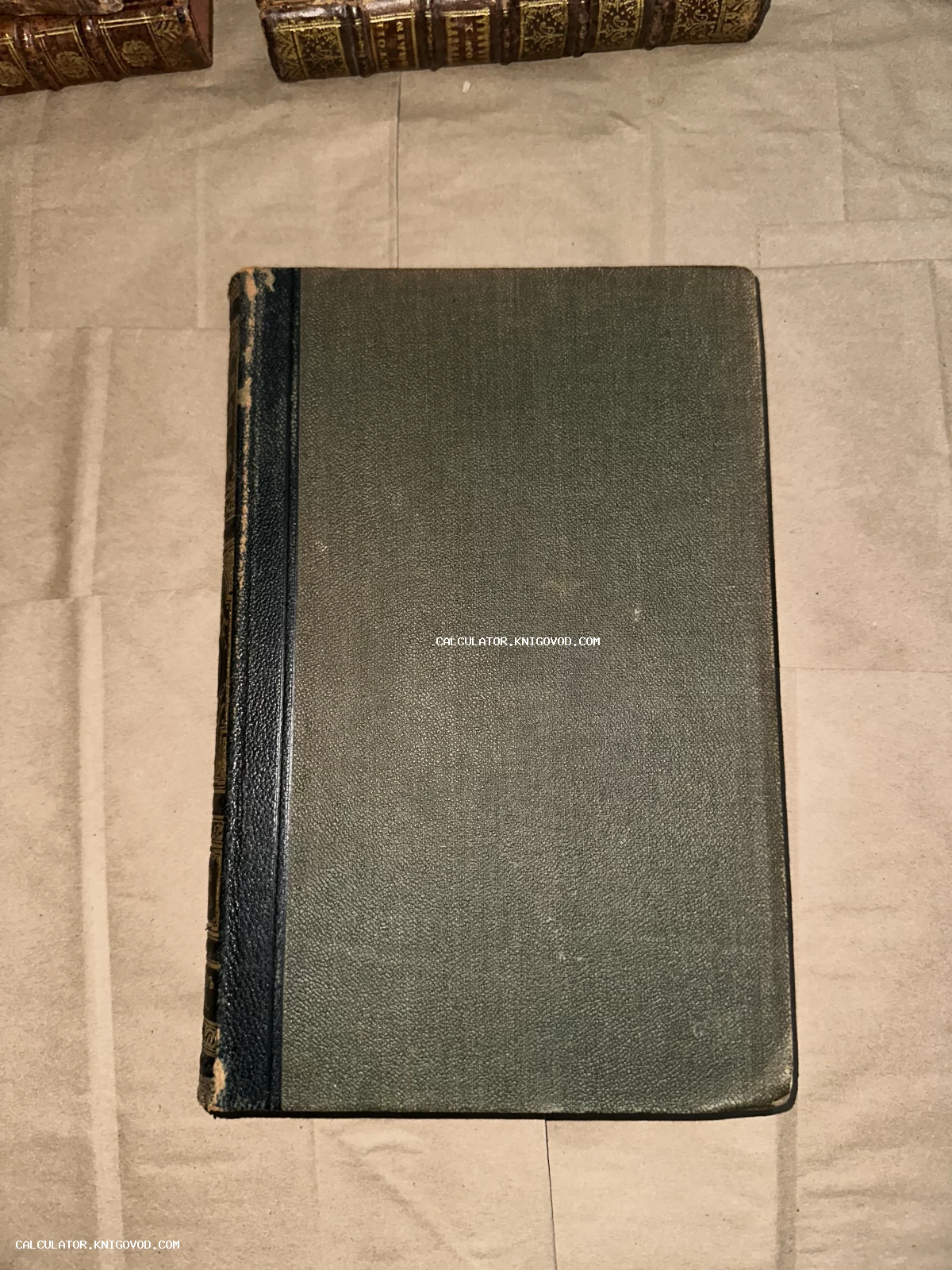 Старинная книга с темно-зеленой фактурной обложкой и кожаным темным корешком.
