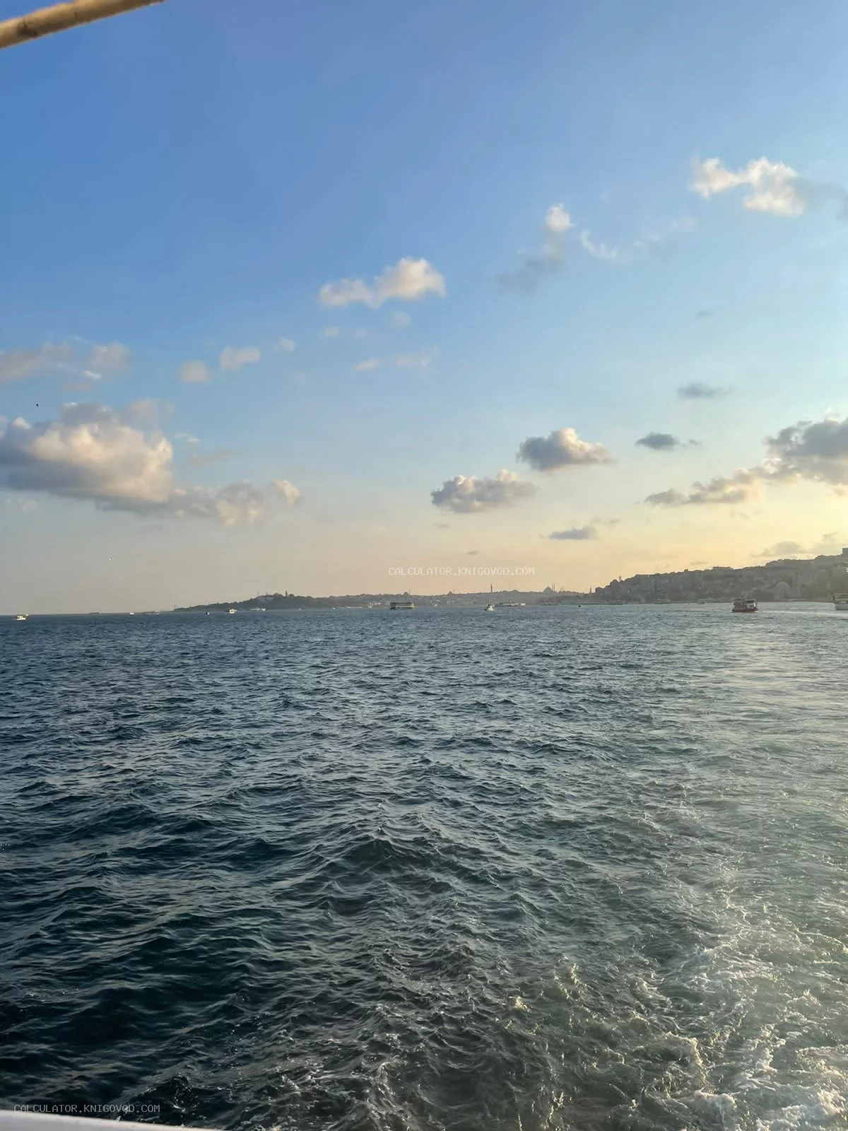 Морской пейзаж с видом на береговую линию города и силуэты минаретов под облачным небом в предзакатный час.