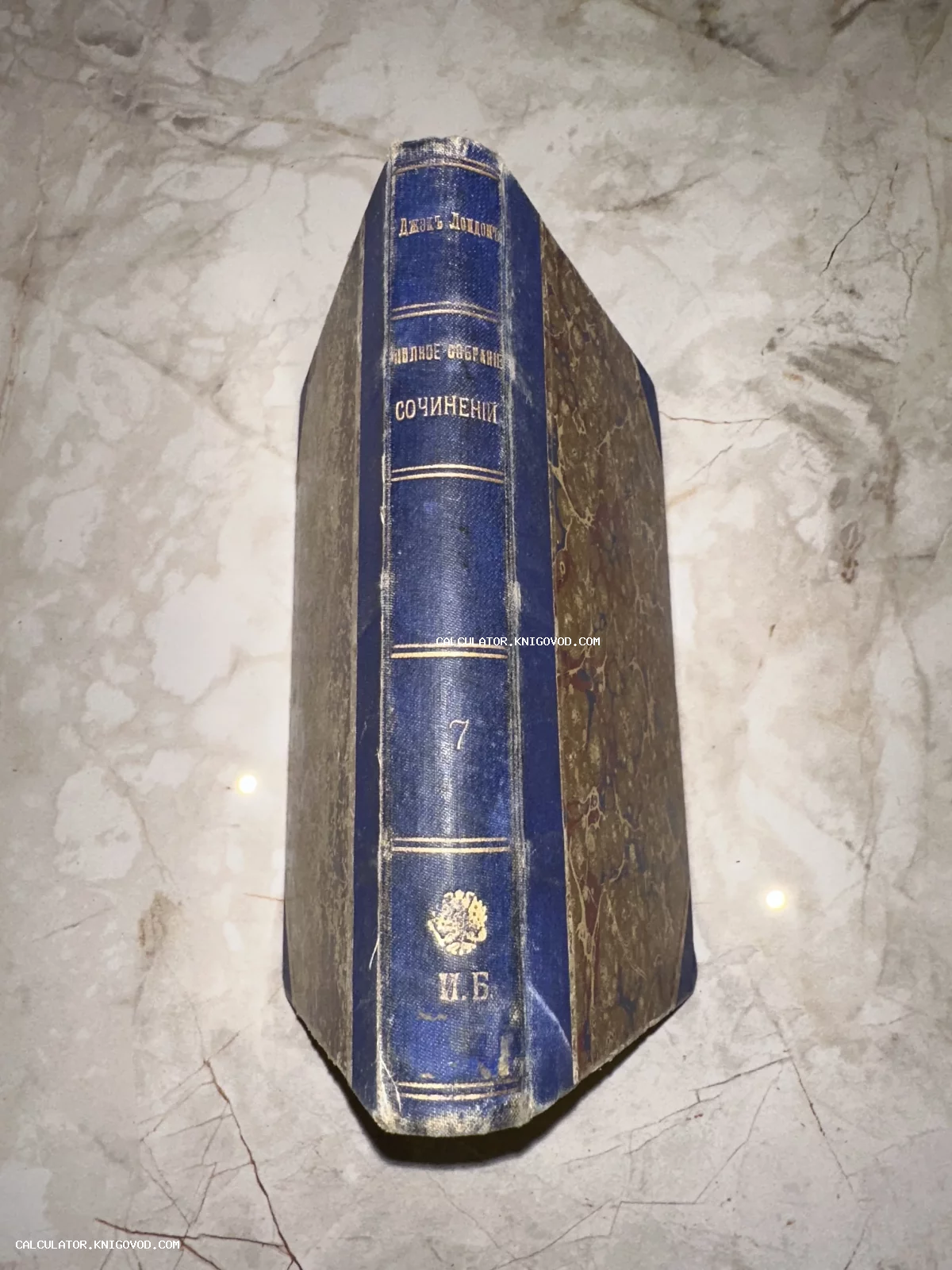 Корешок и обложка антикварной книги Джека Лондона в синем переплете с золотым тиснением и мраморным узором.