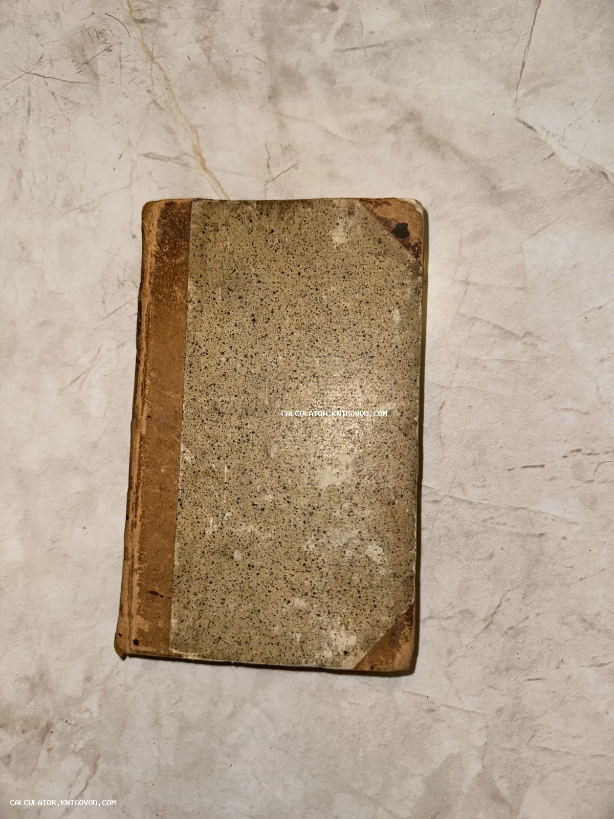 Обложка антикварной книги с характерным крапчатым рисунком и потертым коричневым корешком
