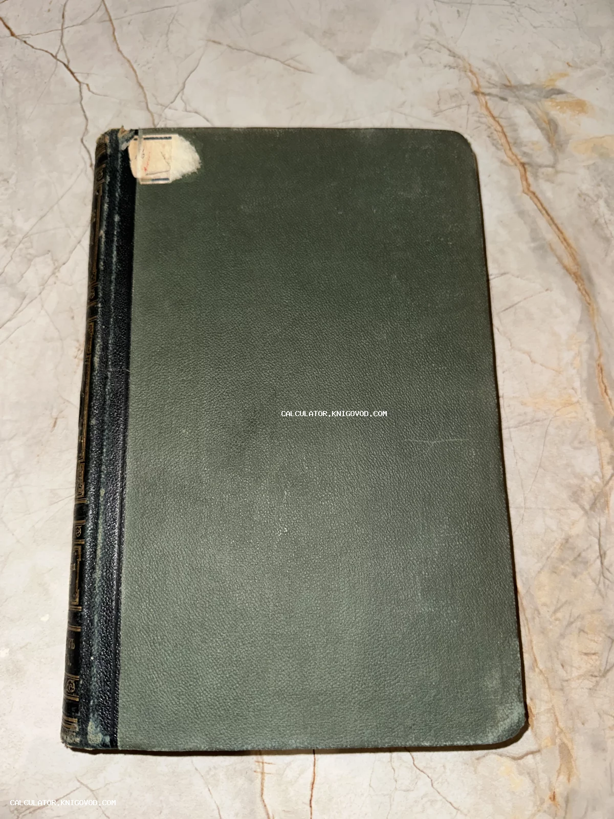 Антикварная книга с темно-зеленой тканевой обложкой и черным кожаным корешком с золотым тиснением.