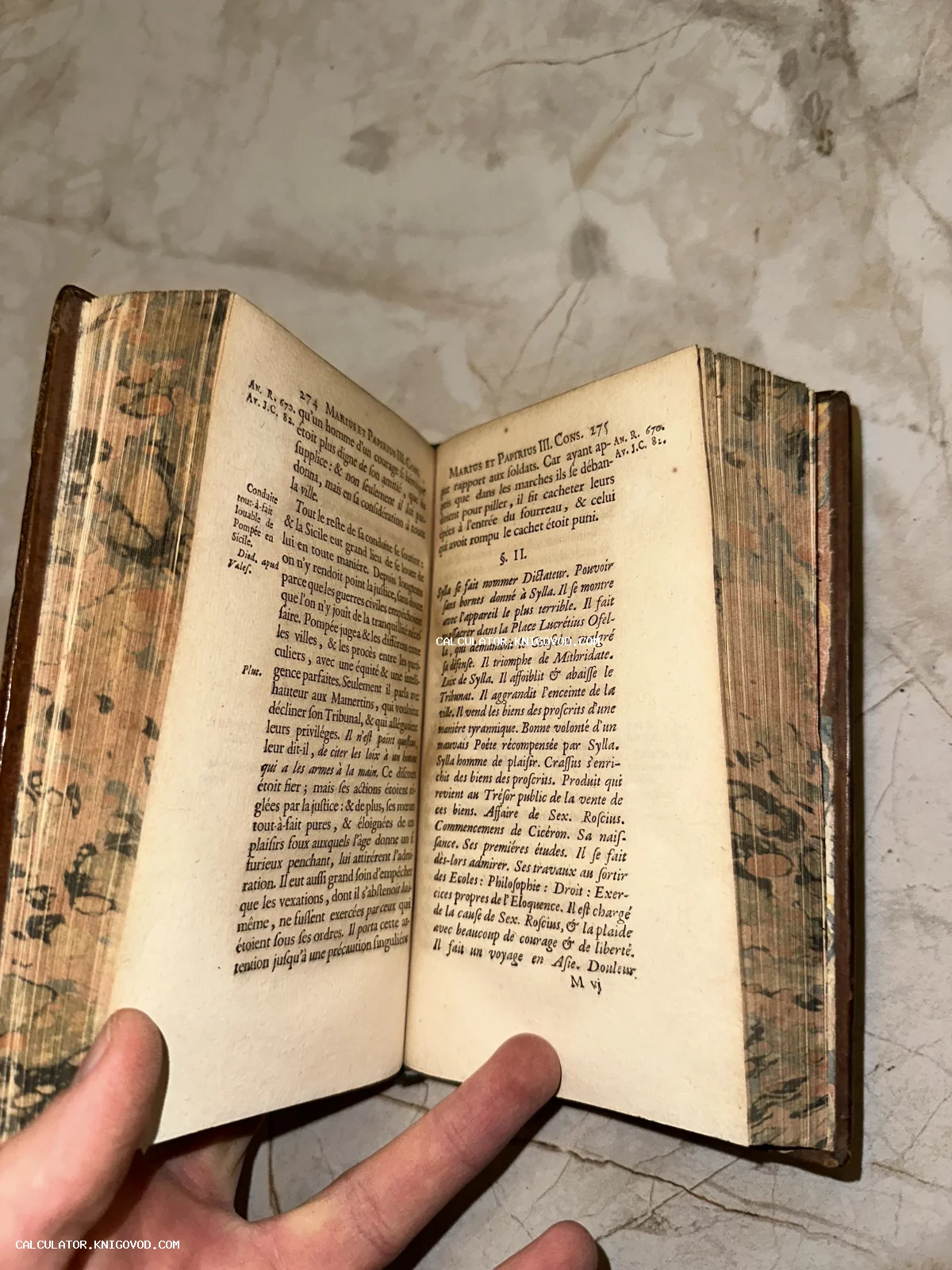 Раскрытая старинная книга на французском языке с мраморным обрезом страниц.