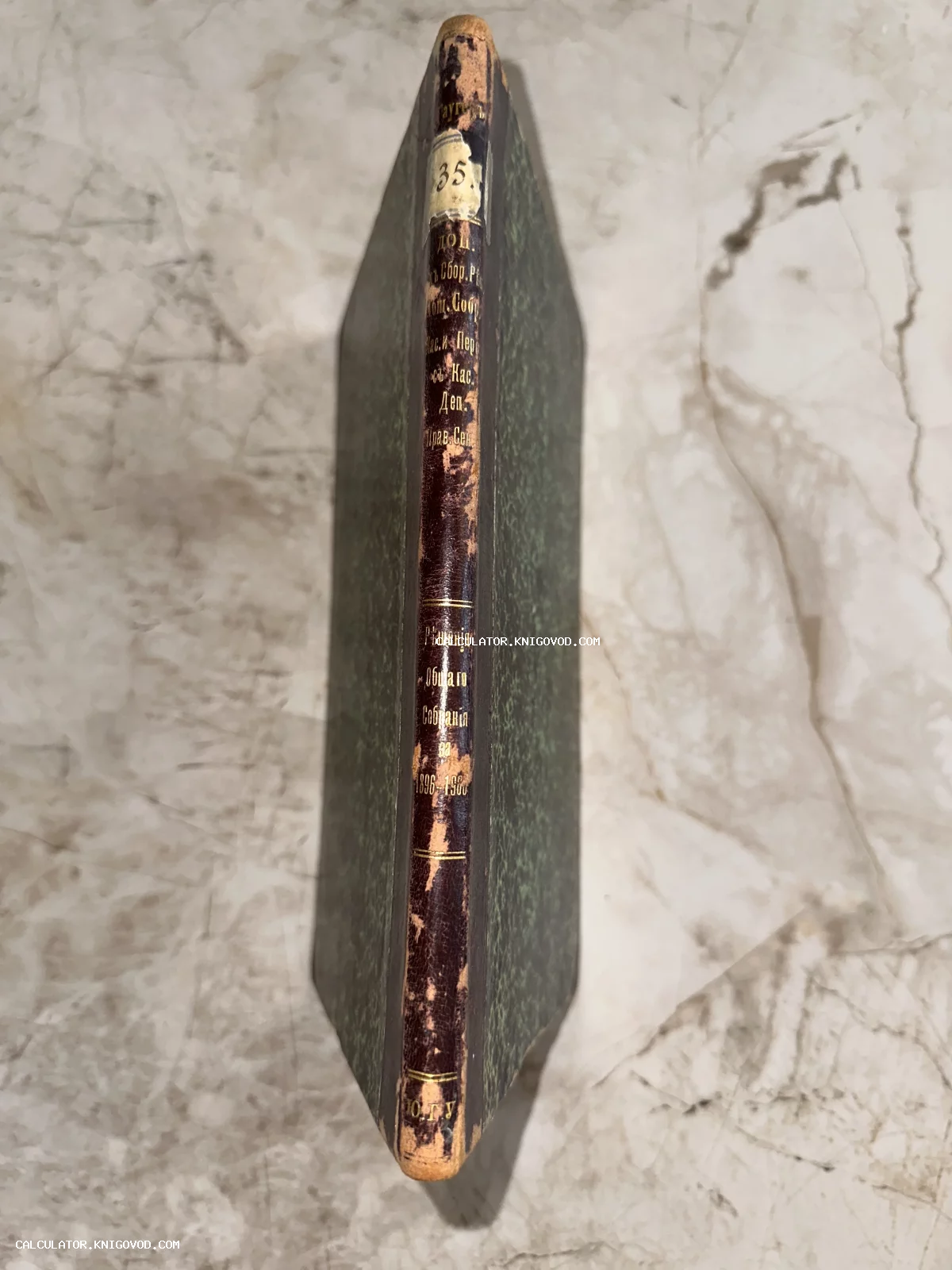 Корешок антикварной книги в полукожаном переплете с золотым тиснением и зелеными мраморными крышками.