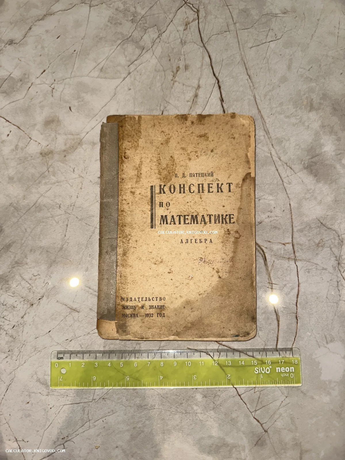 Старинная книга в мягком переплете 1932 года, автор П. Д. Пятецкий, название 'Конспект по математике: Алгебра' на фоне мрамора.