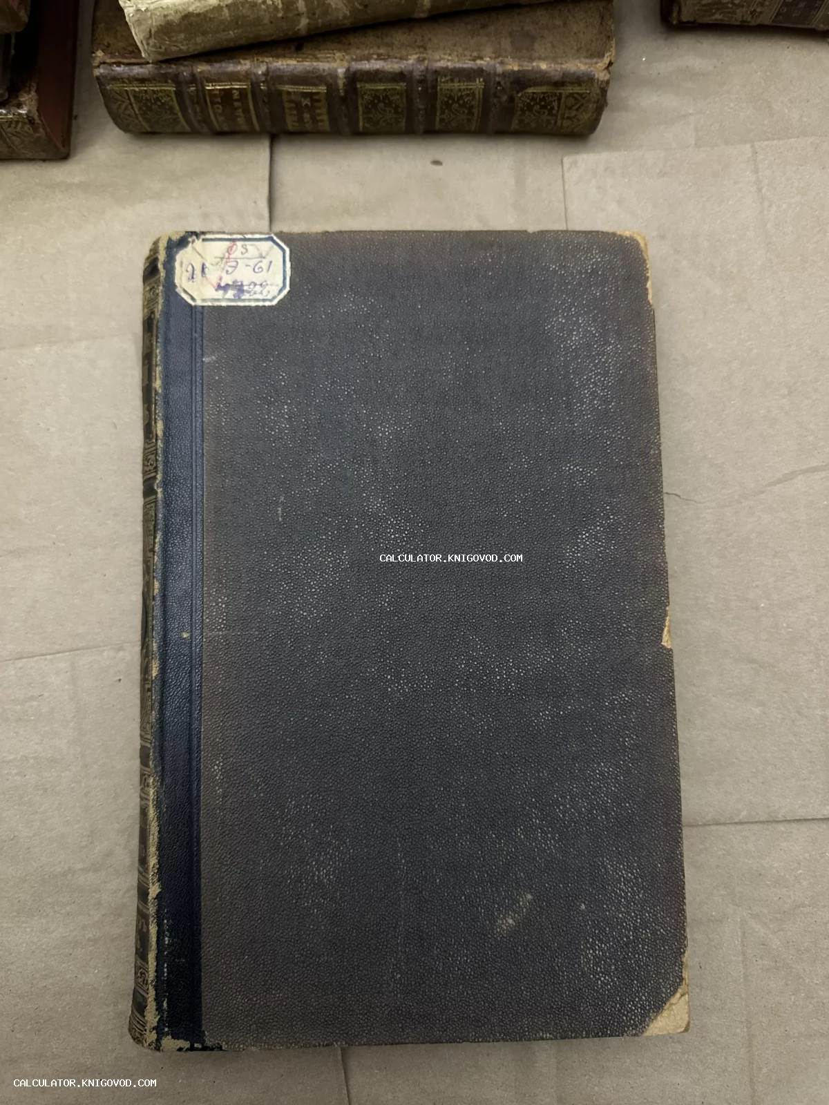 Старинная книга с темной текстурированной обложкой, синим корешком и бумажным ярлыком на лицевой стороне