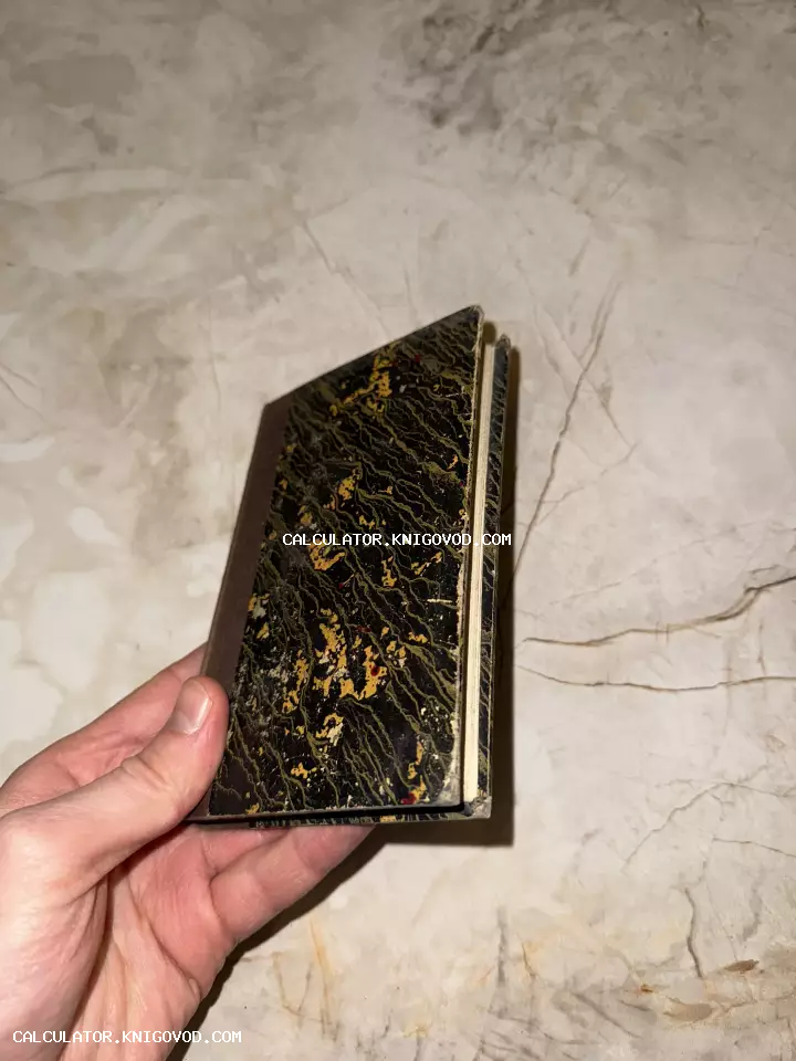 Маленькая старинная книга с обложкой из мраморной бумаги в руке человека на фоне светлого камня.