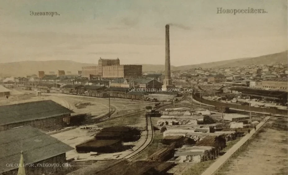 Историческое фото элеватора и промышленной зоны в Новороссийске с видом на железную дорогу и горы на заднем плане.