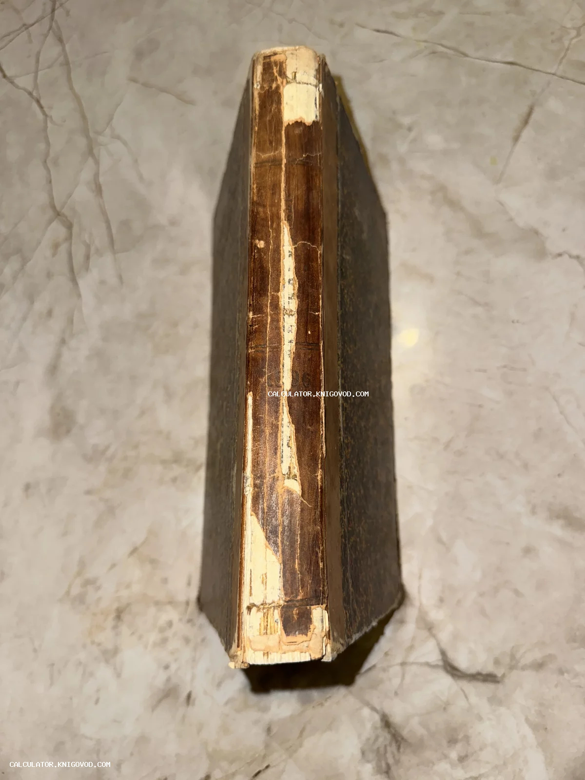 Вид сверху на потертый кожаный корешок старинной книги с повреждениями и следами времени.