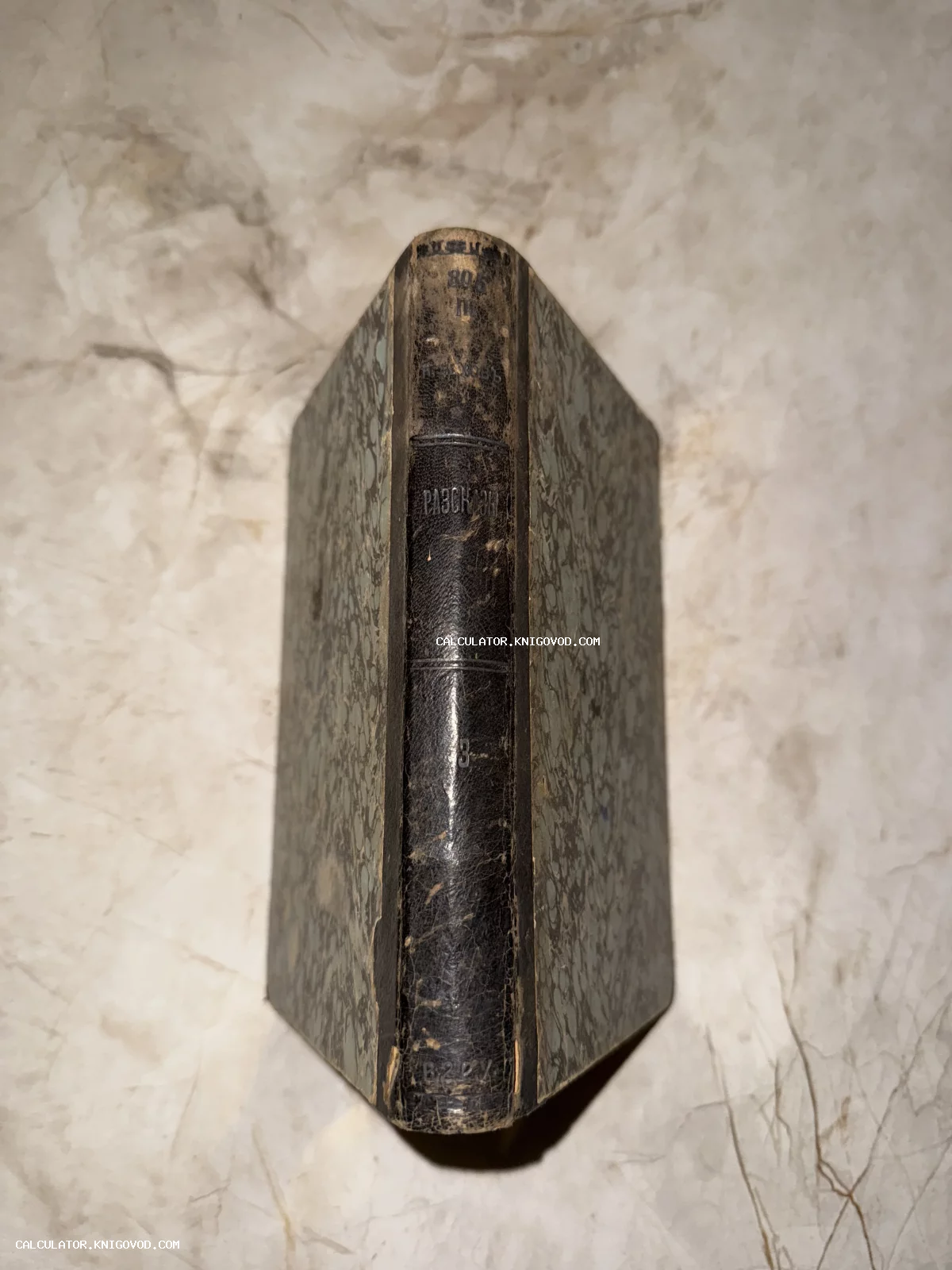 Вид сверху на корешок старинной книги с тиснением 'Рассказы' и обложкой из мраморной бумаги.