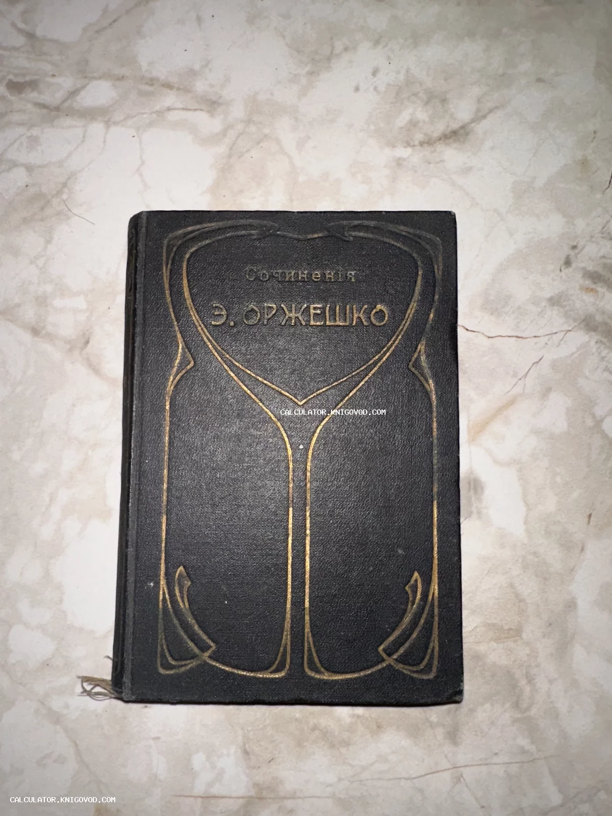 Старинный темный переплет книги «Сочинения Э. Оржешко» с золотым тиснением в стиле модерн на мраморном фоне.