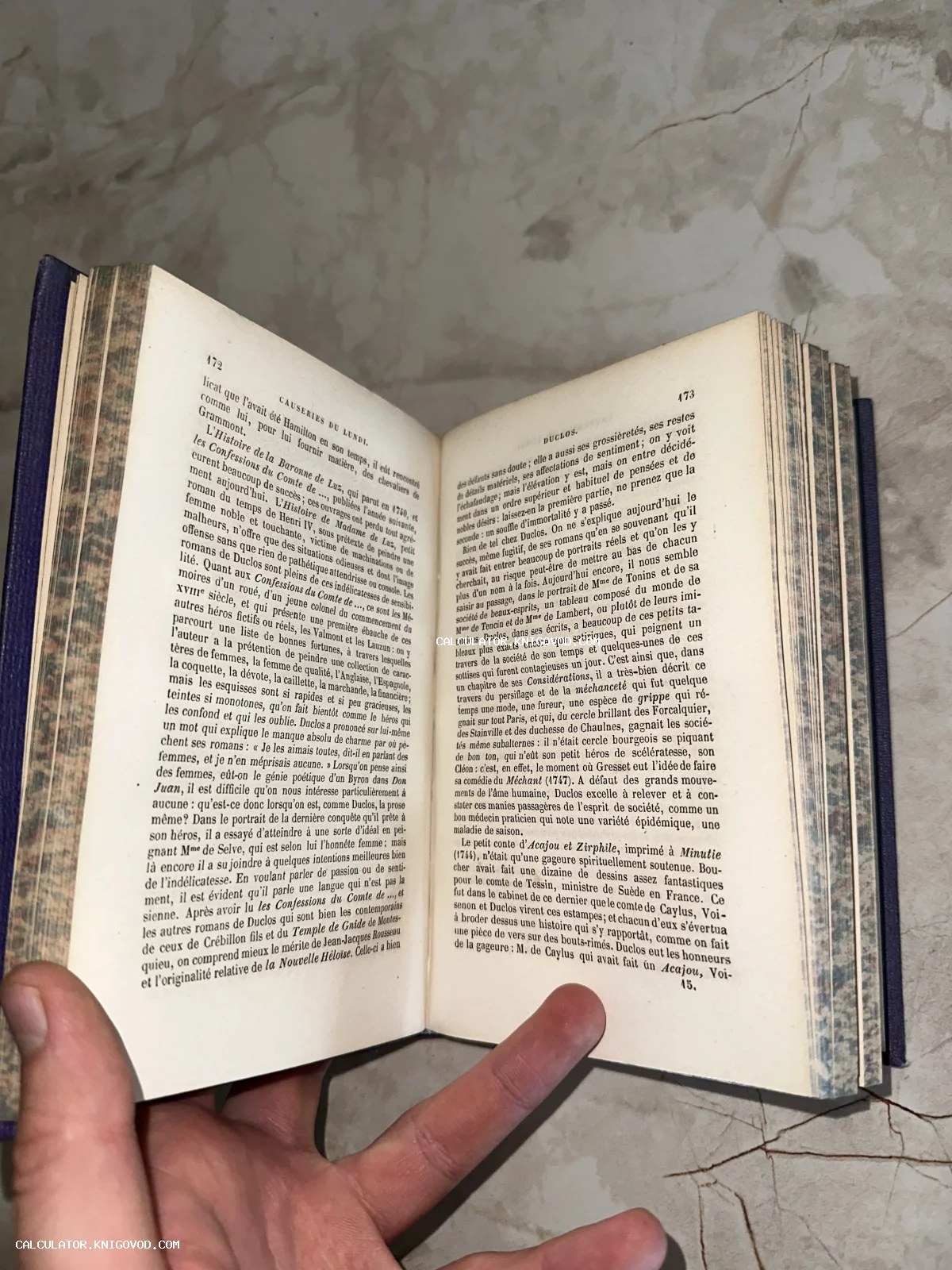 Раскрытая старинная книга на французском языке с пожелтевшими страницами и мраморным обрезом.