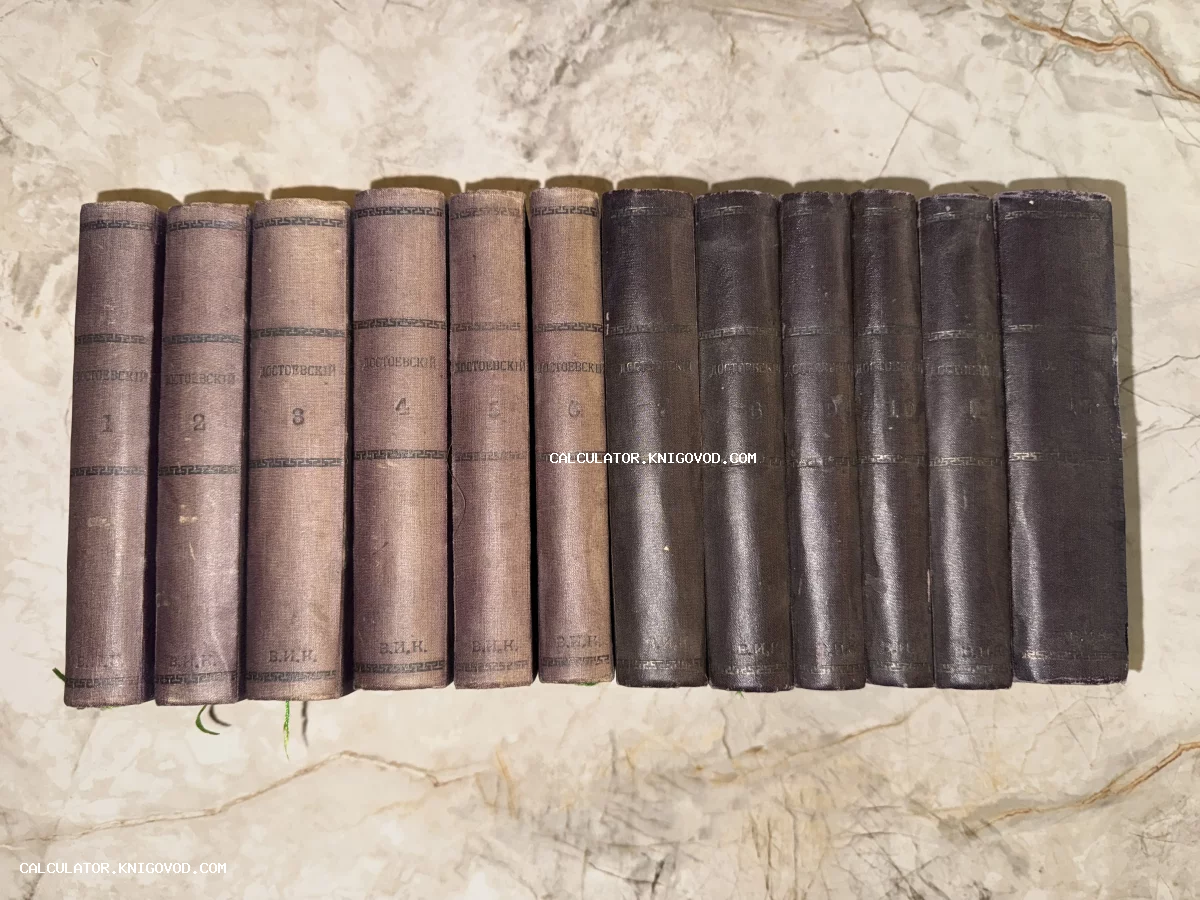 Двенадцать антикварных книг Федора Достоевского в тканевых переплетах, выстроенных в ряд на мраморной поверхности.