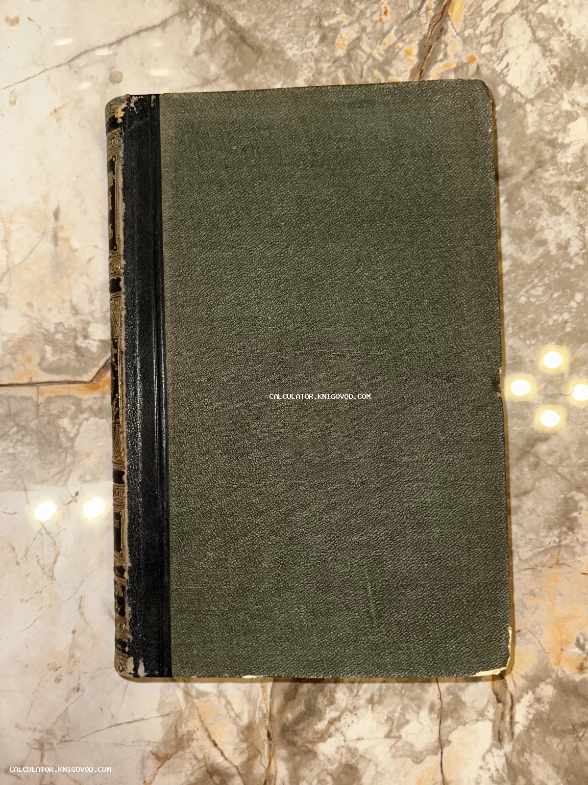 Старинная книга с темно-зеленым матерчатым переплетом и кожаным корешком с золотым тиснением на мраморной поверхности