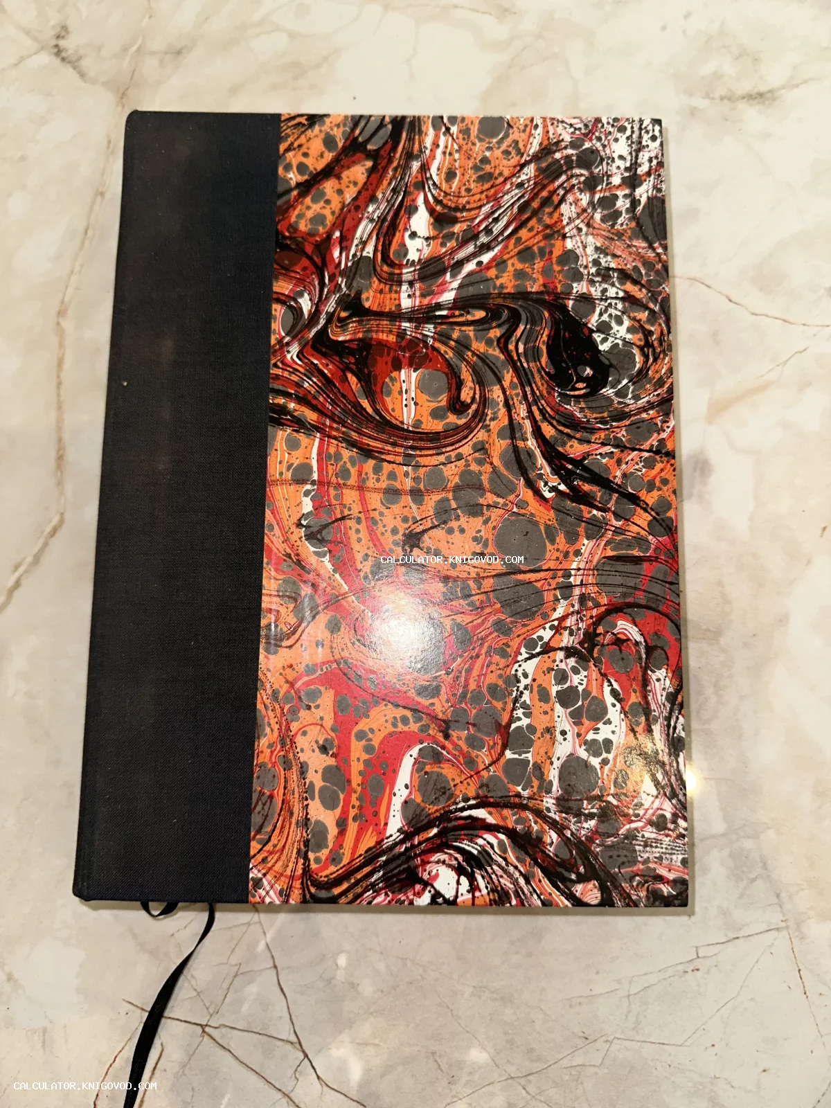Старинная книга или альбом в полукожаном переплете с обложкой из яркой мраморной бумаги с оранжевыми и черными разводами.