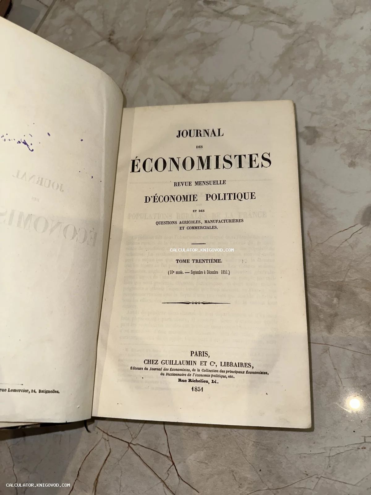 Титульный лист французского экономического издания 1851 года Journal des Économistes на мраморном фоне.