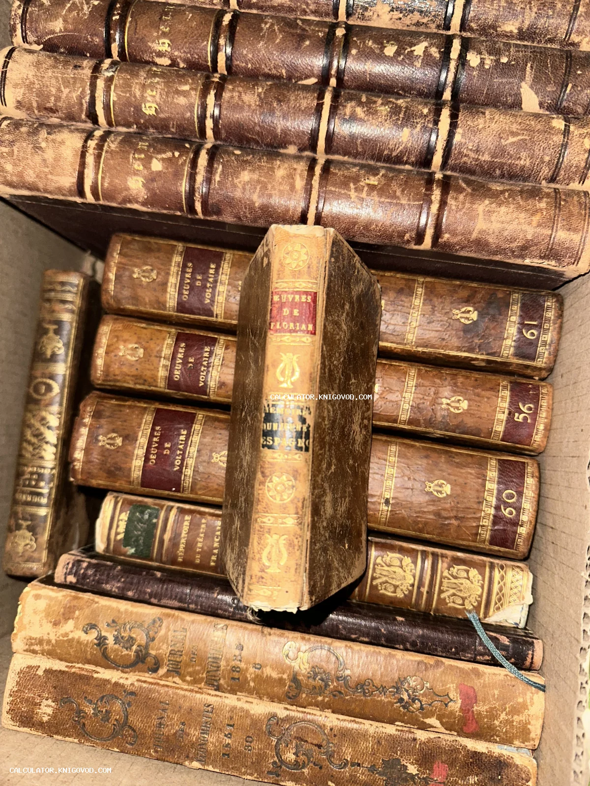 Старинные французские книги в кожаных переплетах с золотым тиснением, включая тома Вольтера и Флориана.