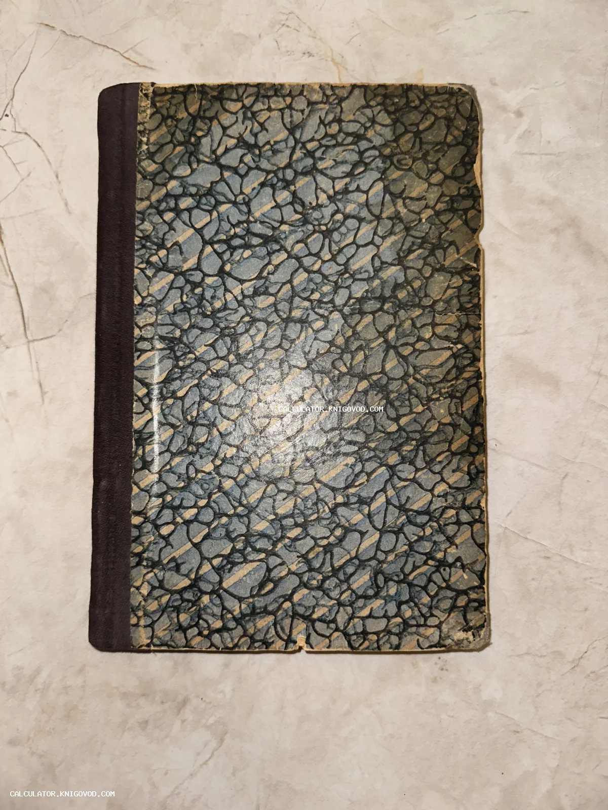 Обложка старой тетради или книги с мраморным узором в серо-голубых тонах и темным тканевым корешком.