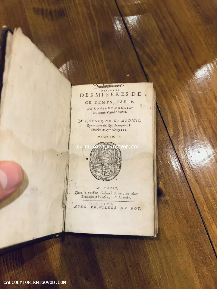 Титульный лист старинной французской книги 1597 года с посвящением Екатерине Медичи на деревянном столе.