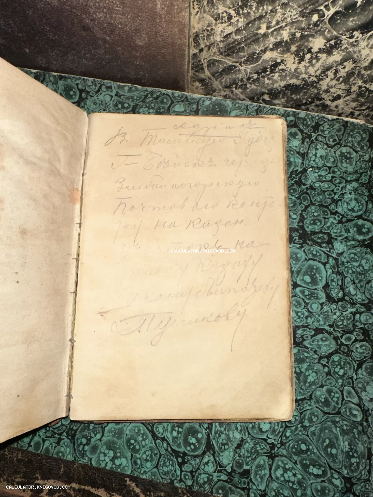 Разворот старинной книги с рукописным текстом на пожелтевшей бумаге на фоне зеленой мраморной обложки.