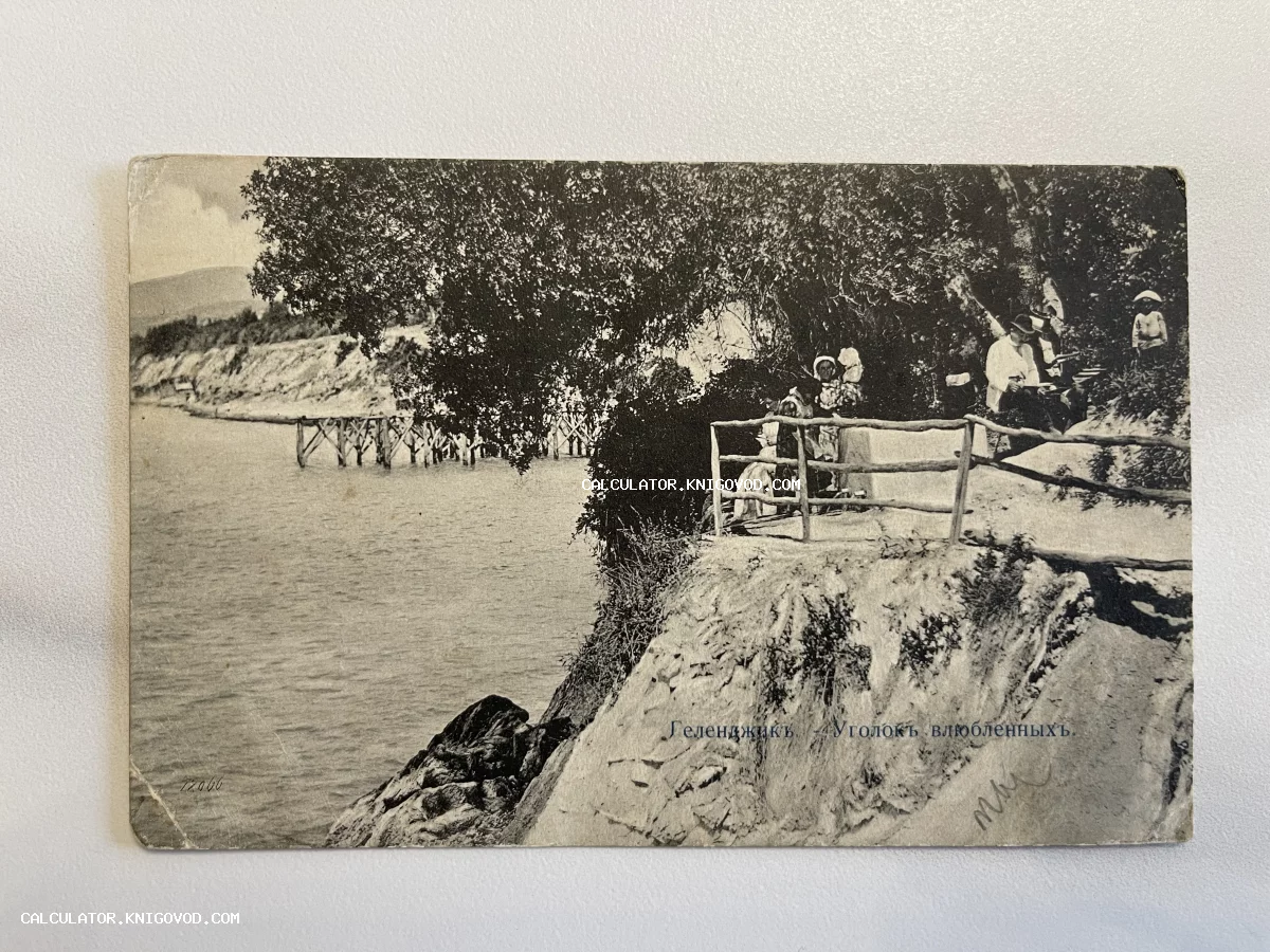 Старинная черно-белая открытка с видом на побережье Геленджика, на которой изображены люди в костюмах начала XX века на скалистом берегу у моря.