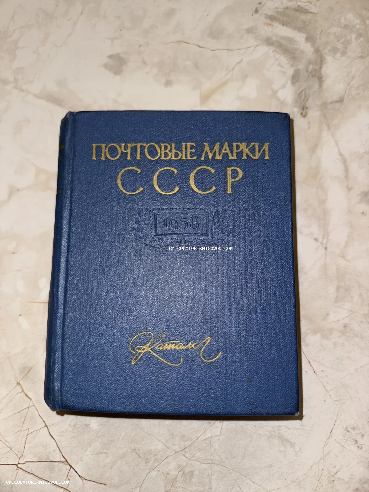 Синяя твердая обложка книги с золотым тиснением «Почтовые марки СССР 1958» на мраморном фоне.