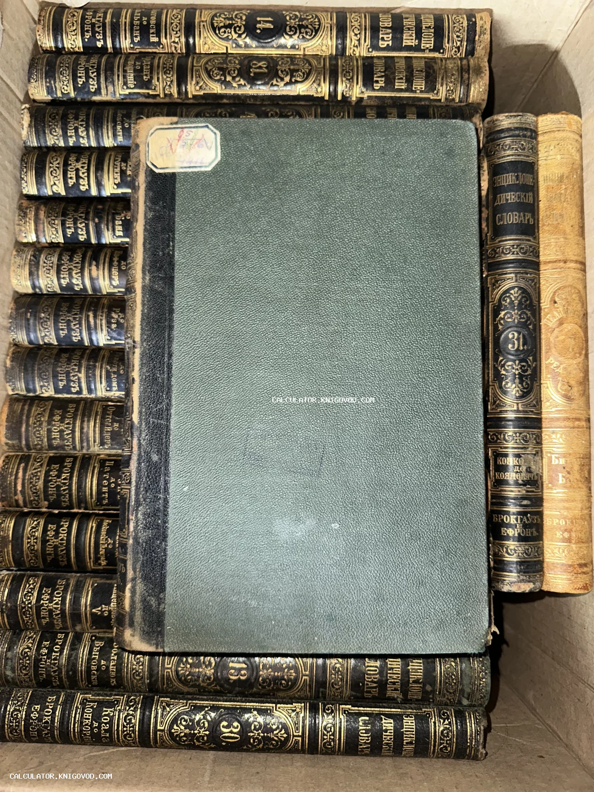 Старинные книги в полукожаных переплетах с золотым тиснением на корешках, расположенные в коробке, вид сверху.