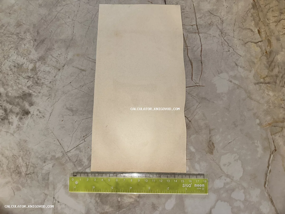 Чистый лист старинной пожелтевшей бумаги вертикальной формы с измерительной линейкой у основания на мраморном фоне.