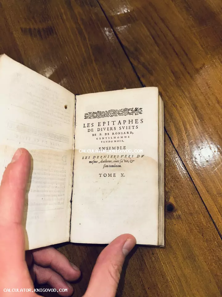Раскрытая старинная книга на французском языке со стихами Пьера де Ронсара на деревянном столе.