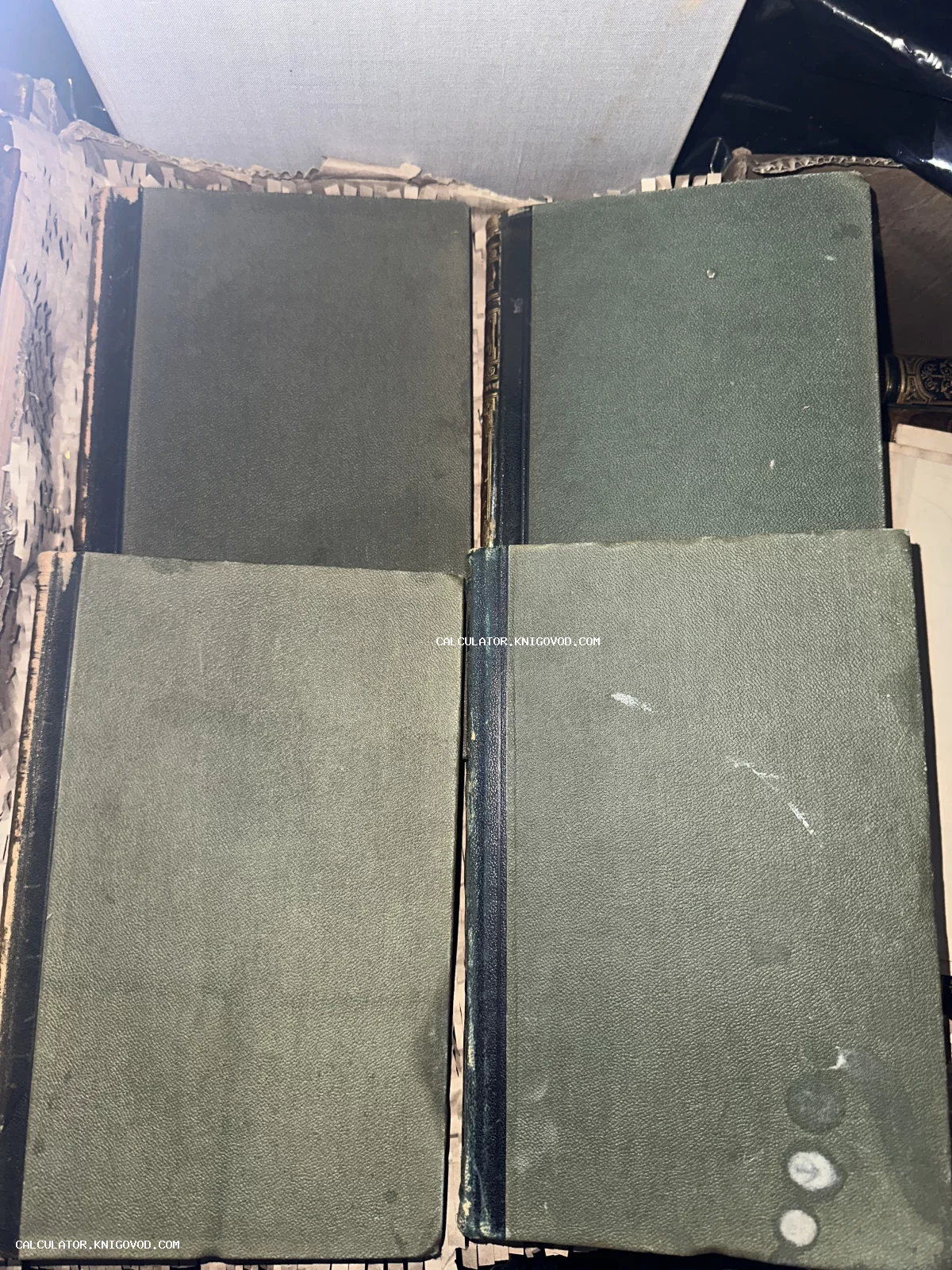 Четыре старинные книги с темно-зелеными текстурированными обложками и темными корешками, лежащие вместе.